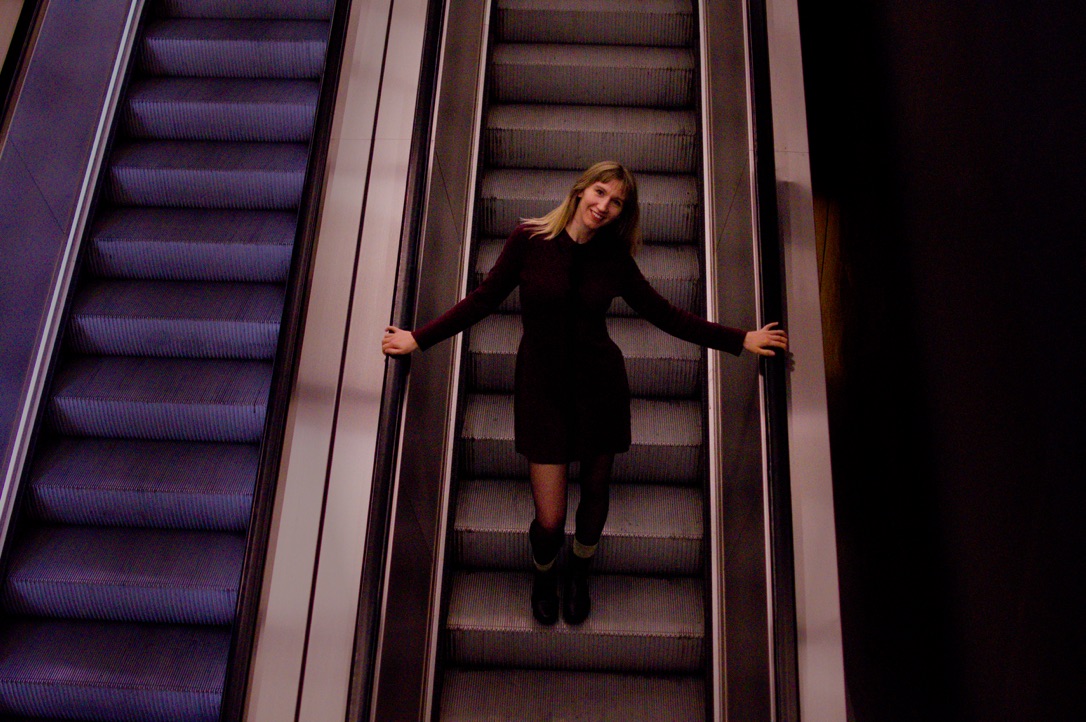 On an escalator, mid-step, grinning